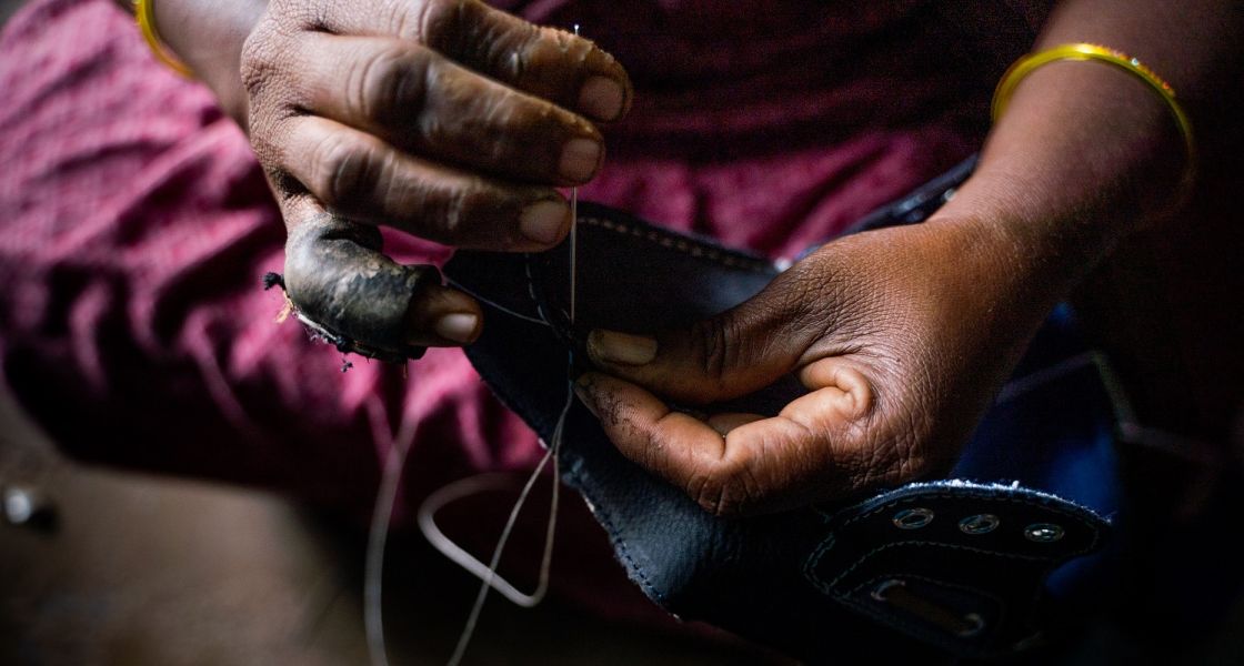 In Südasien produzieren die Arbeiter*innen der Schuhindustrie unter katastrophalen Bedingungen in mühseliger Handarbeit. Bild: Together for Decent Leather Jemand sticht eine Nadel mit Faden durch einen Lederschuh.