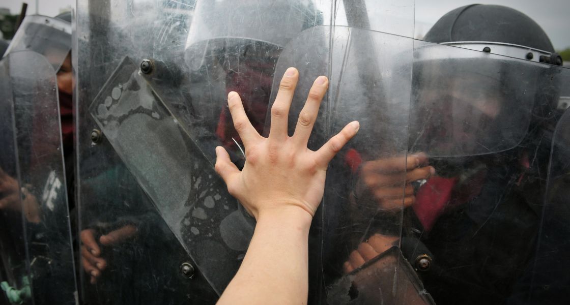 eine Gruppe gut geschützter Polizist*innen wehrt Demonstrant*innen ab