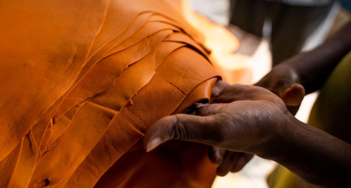 Hände halten einen Stapel orangefarbenen Leders