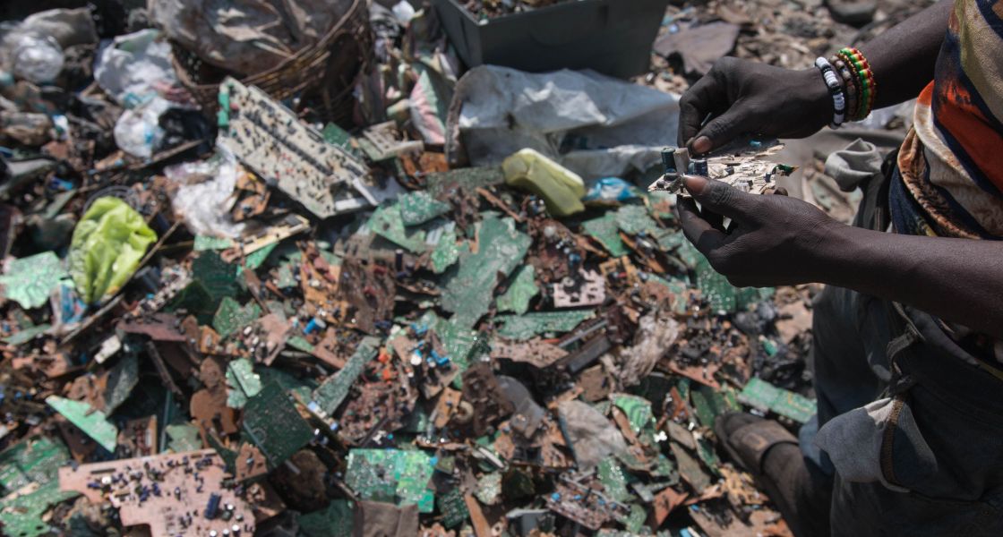Zwei Schwarze Frauenhände sortieren elektroschrott über einem großen Berg Elektroschrott