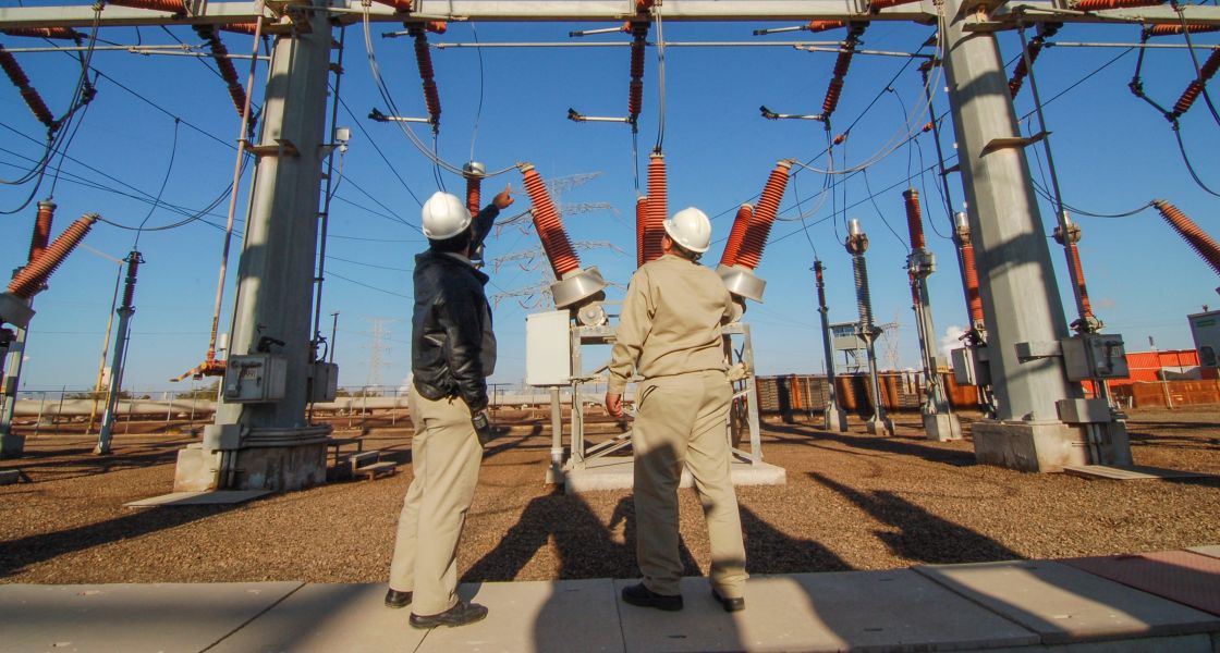Zwei Menschen stehen vor einem Umspannwerk
