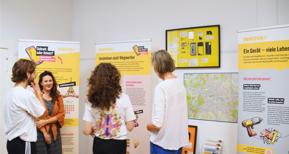 Vier Personen betrachten die Info-Aufsteller der Ausstellung
