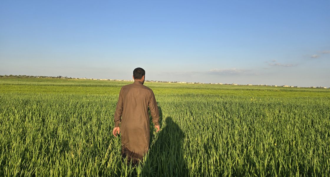 Foto von einem Mann in traditioneller syrischer Kleidung in Rückansicht auf einem Feld
