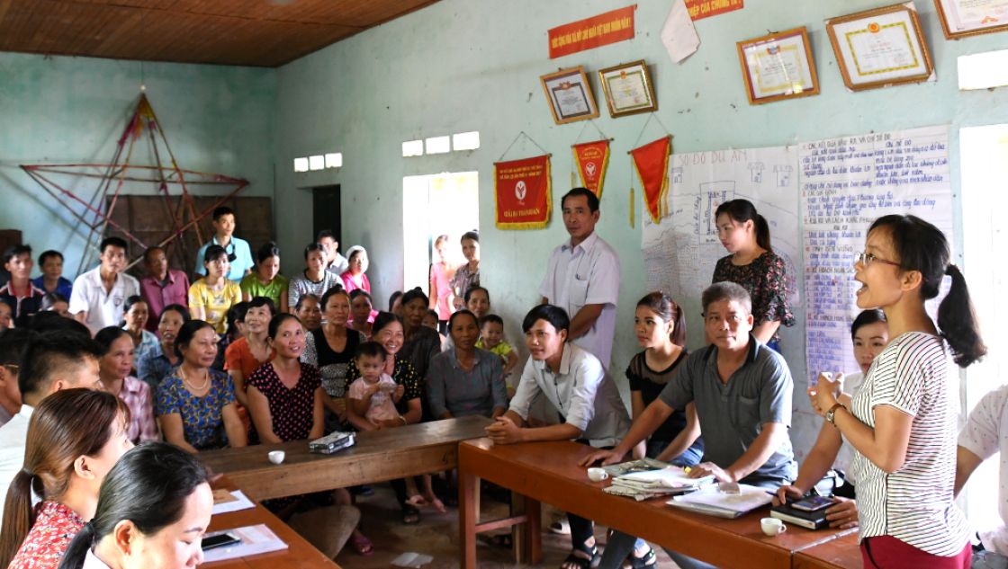 Eine Dorfversammlung in der Gemeinde Tan Loi in Vietnam Eine Frau spricht und viele Zuhörer in einem Raum