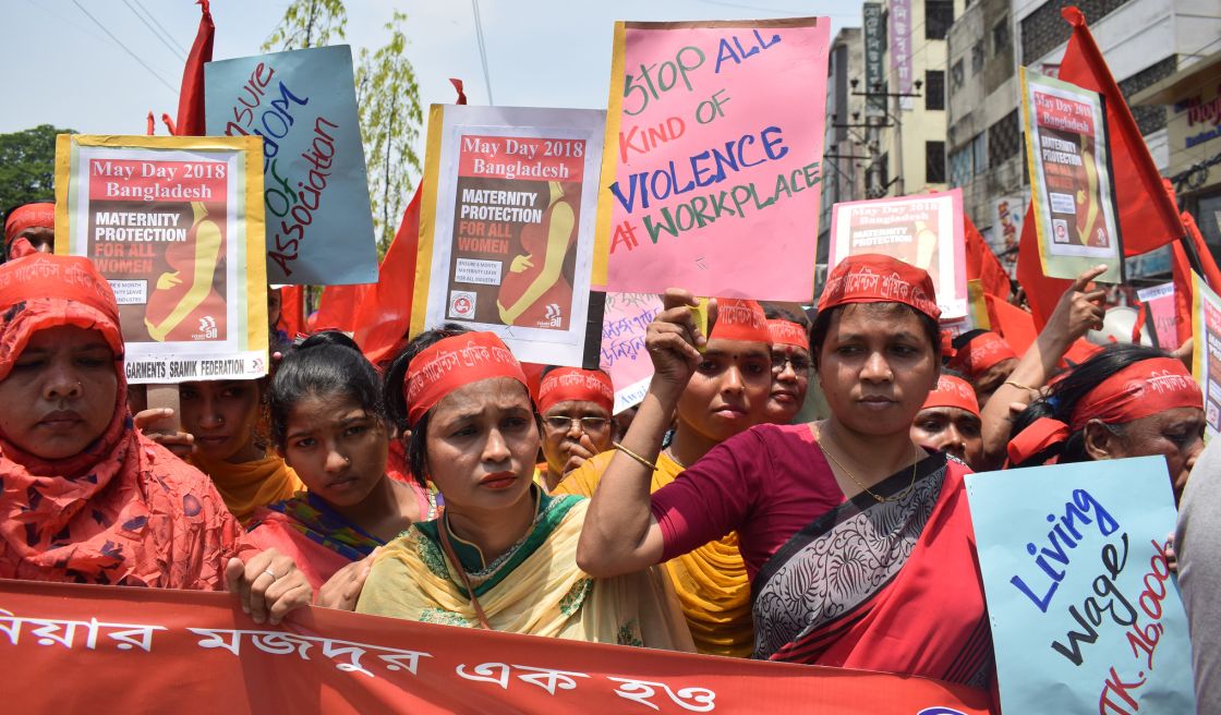 Frauen mit roten Stirnbändern tragen eines großes Protestbanner vor sich