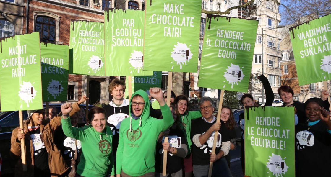Eine Menschengruppe - meist in grünen Hoodies - zeigen Protestschilder hoch und ihre Fäuste