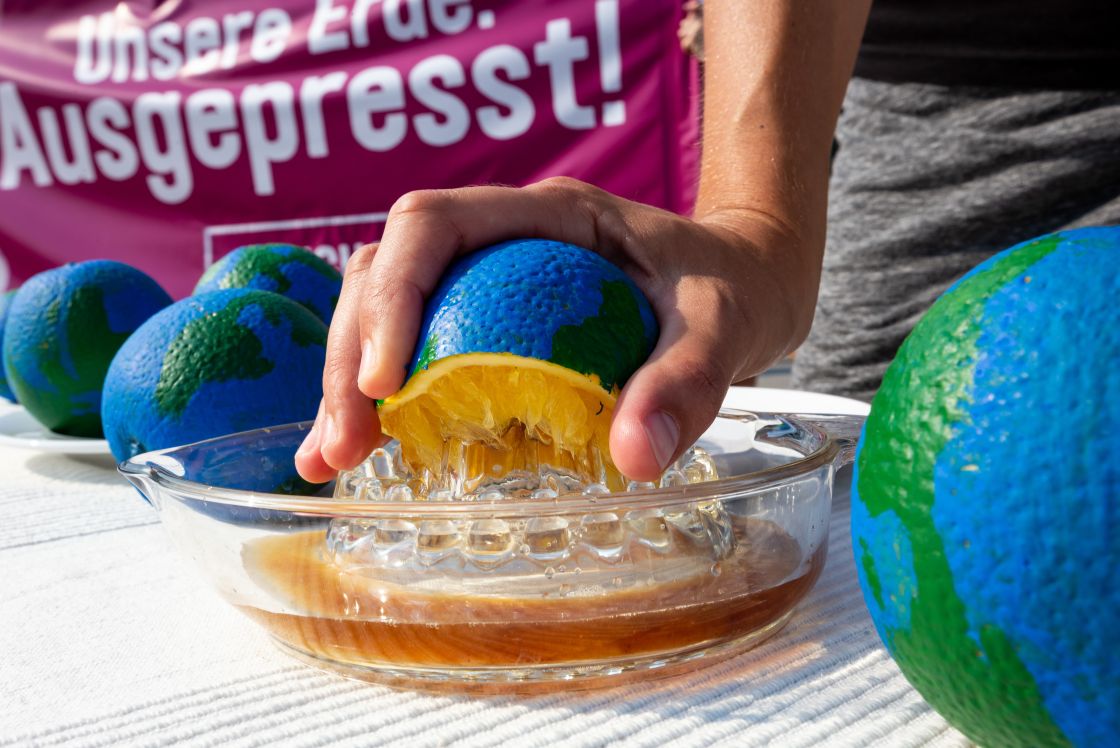 Eine halbe Pampelmuse, die außen wie eine Weltkugel angemalt ist, wird auf eine Zitronenpresse gelegt