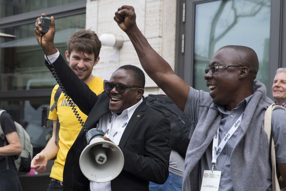 Zwei Männer strecken ihre Faust nach oben. Ein dritter lächelt die beiden an.