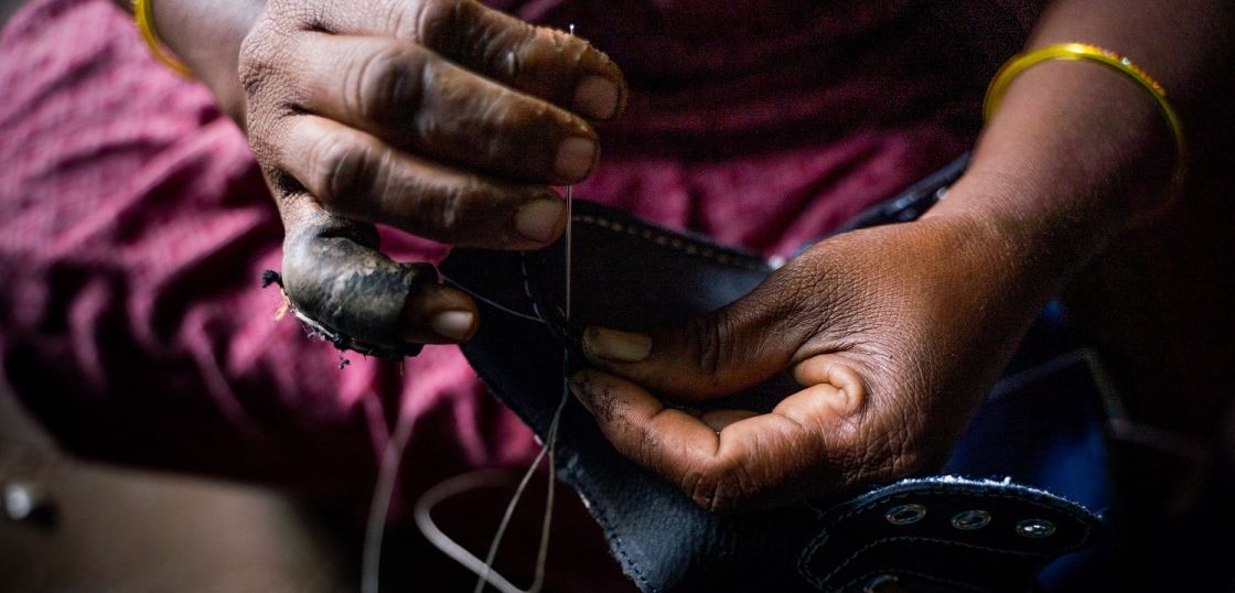 In Südasien produzieren die Arbeiter*innen der Schuhindustrie unter katastrophalen Bedingungen in mühseliger Handarbeit. Bild: Together for Decent Leather Jemand sticht eine Nadel mit Faden durch einen Lederschuh.