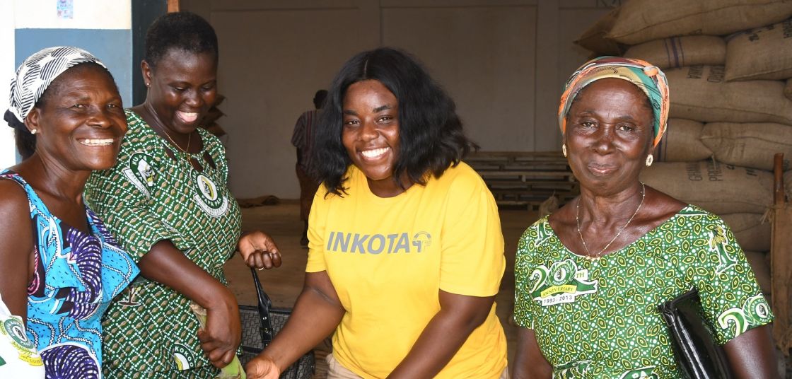 Kakaobäuerinnen in Ghana bei einem Austauschtreffen Vier Kakaobäuerinnen stehen in einem Lager
