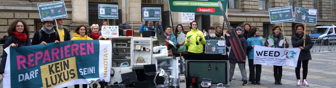 Eine Gruppe Menschen mit Schildern und kaputten Elektrogeräten vor dem Abgeordentenhaus in Berlin
