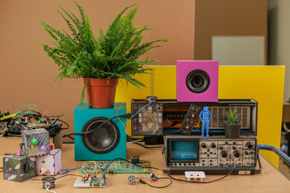 Foto mit verschiedenen mit Elektro- und Elektronikgeräten und einer Grünpflanze