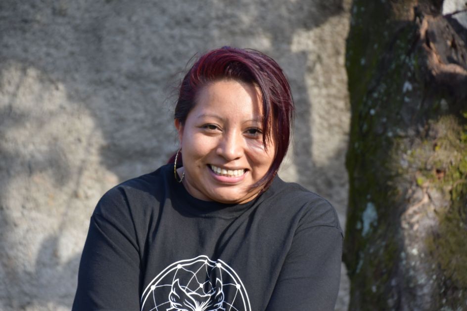 Eine Frau mit schwarzem Pulli schau lächelnd in die Kamera.