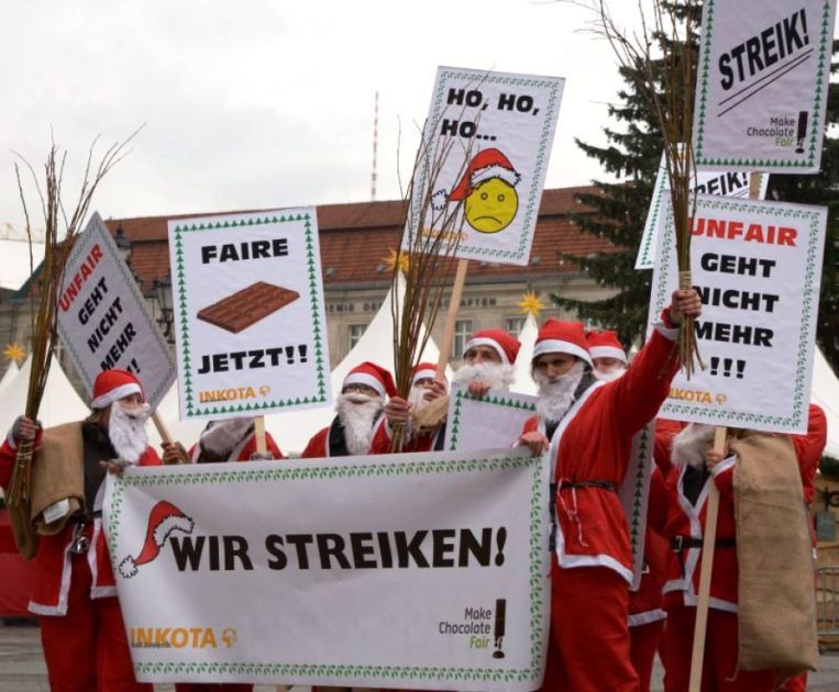 Mehrere Menschen als Weihnachtsmänner verkleidet mit Protestschildern in den Händen