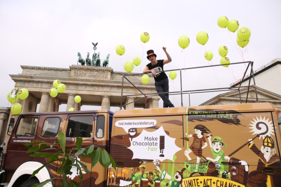 Ein großer Bus mit Schokoladen bemalt und grüne Luftballons vor dem Brandenburger Tor