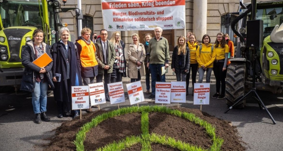 Menschen stehen zusammen mit zwei grünen Traktoren und einem Peace-Zeichen aus Graus vor einem Haus