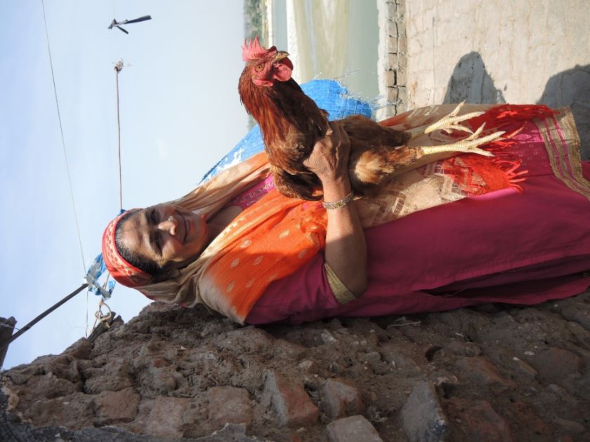  Heimarbeiterin, die zu Hause Lederriemen z.B. für Sandalen oder Taschen flicht, mit einem ihrer Hühner am Ufer des Ganges. | © INKOTA