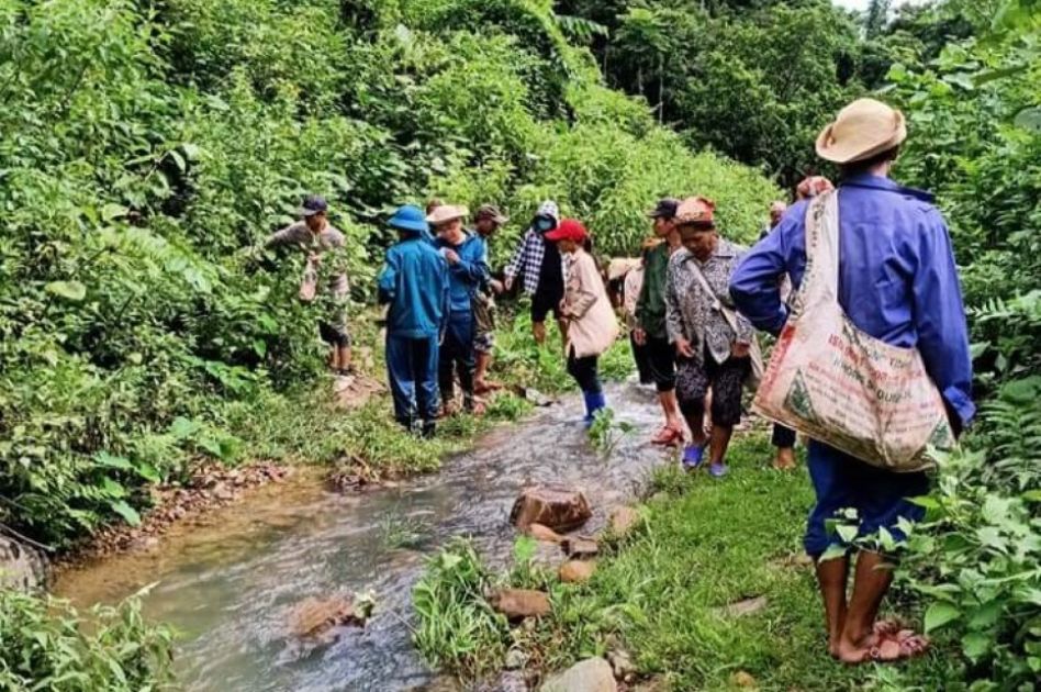 Mehrere Frauen und Männer laufen an einem Fluss im Wald