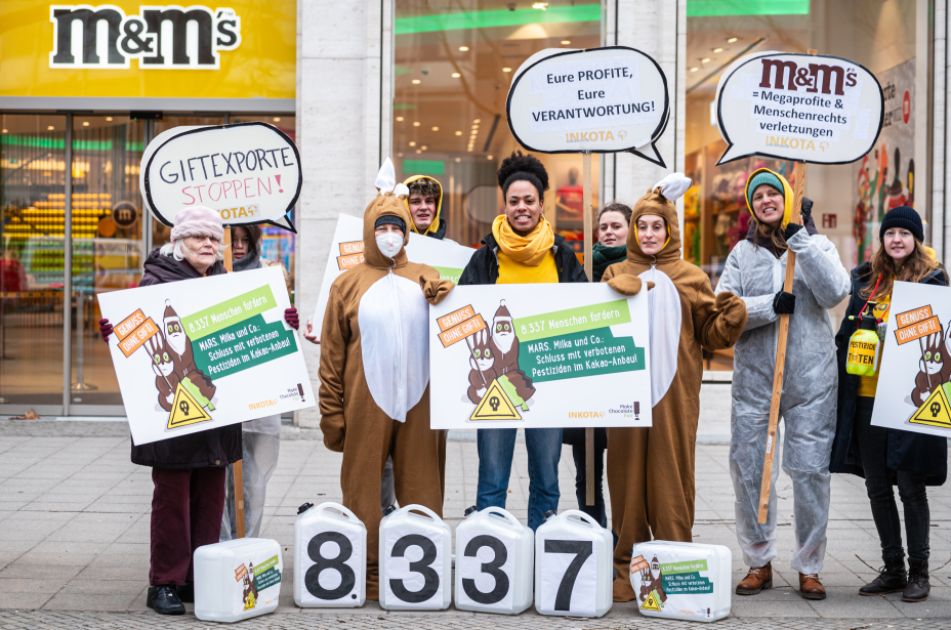 INKOTA-Aktivist*innen protestieren vor dem MARS M&M-Store in Berlin gegen verbotene Pestizide im Kakaoanbau