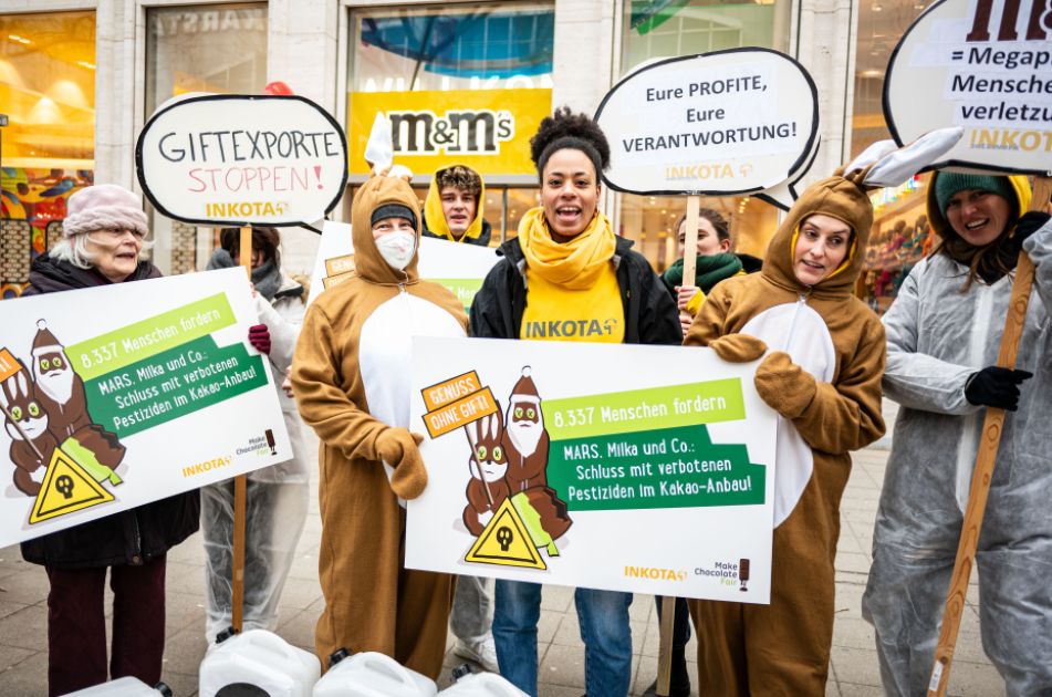 Gruppenfoto, INKOTA-Aktivist*innen protestieren vor dem MARS M&M-Store in Berlin gegen verbotene Pestizide im Kakaoanbau