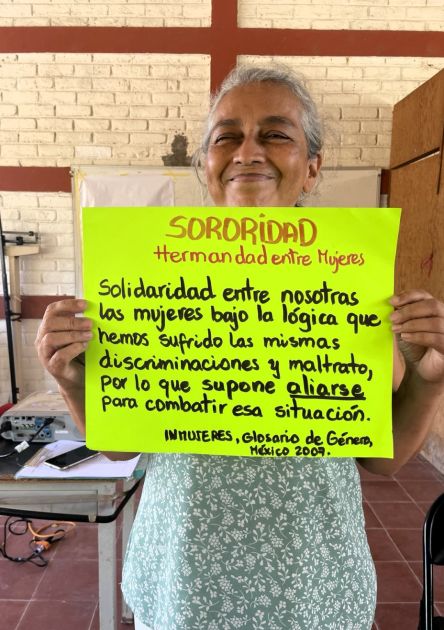 Eine Frau hält ein selbstgebasteltes Schild hoch auf dem auf spanisch Schwesternschaft steht.