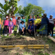 Gruppenfoto mit Projektteilnehmerinnen und Kindern aus El Salvador bei einer Baumpflanz-Aktion.