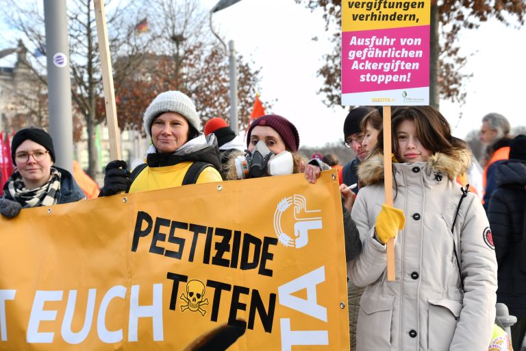 Menschen auf einer Demo am Reichstag in Berlin mit Bannern und Schildern mit der Aufschrift Pestizide töten