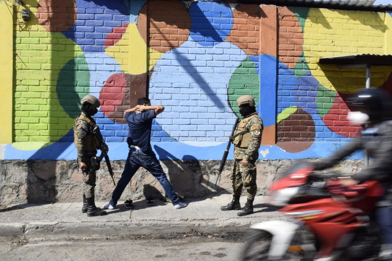Ein Mann in El Salvador wird von zwei uniformierten Militärs verhaftet