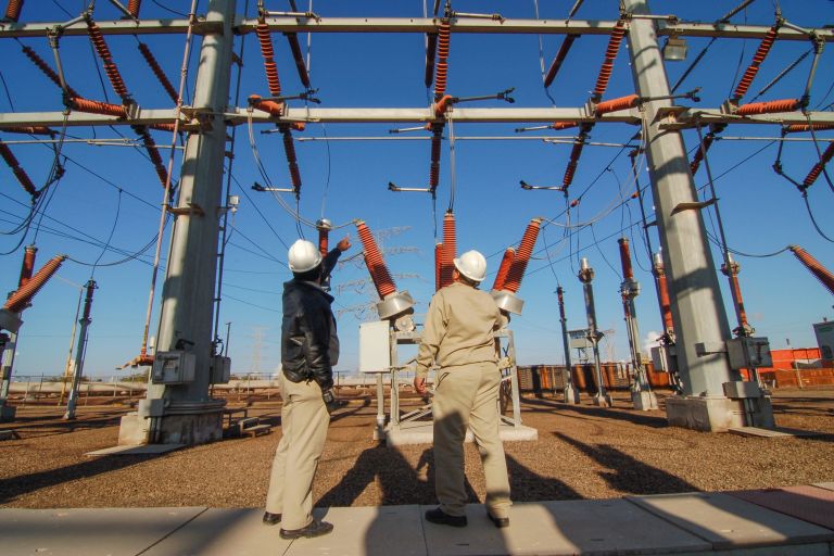 Zwei Menschen stehen vor einem Umspannwerk