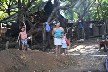 Eine Frau mit zwei Kindern vor einer einfachen Biogas-Anlage
